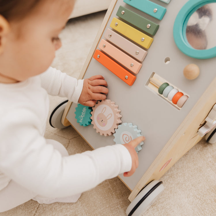 Child playing with a colorful wooden toy on a carpeted floor