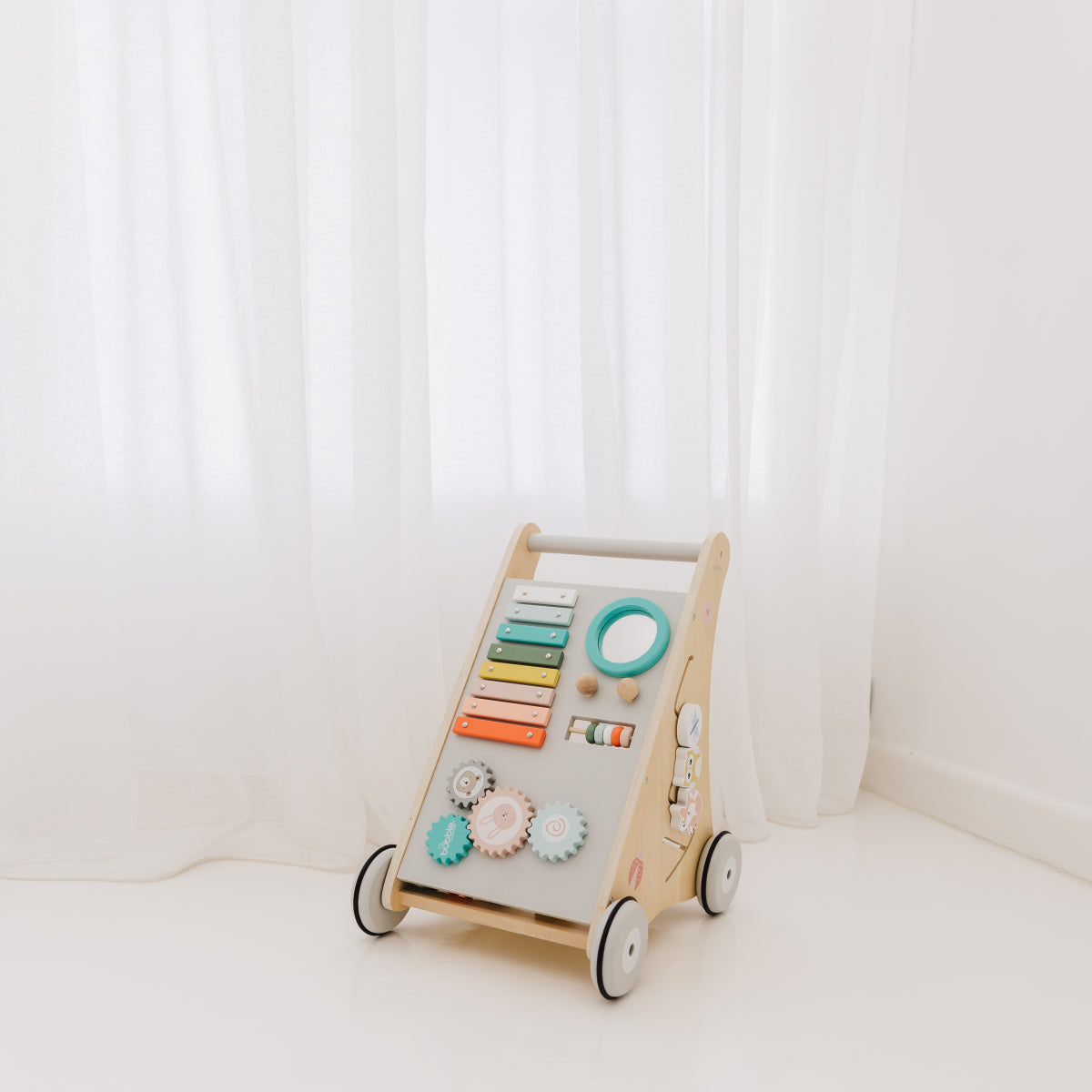 Wooden children's activity walker with colorful knobs on a white background