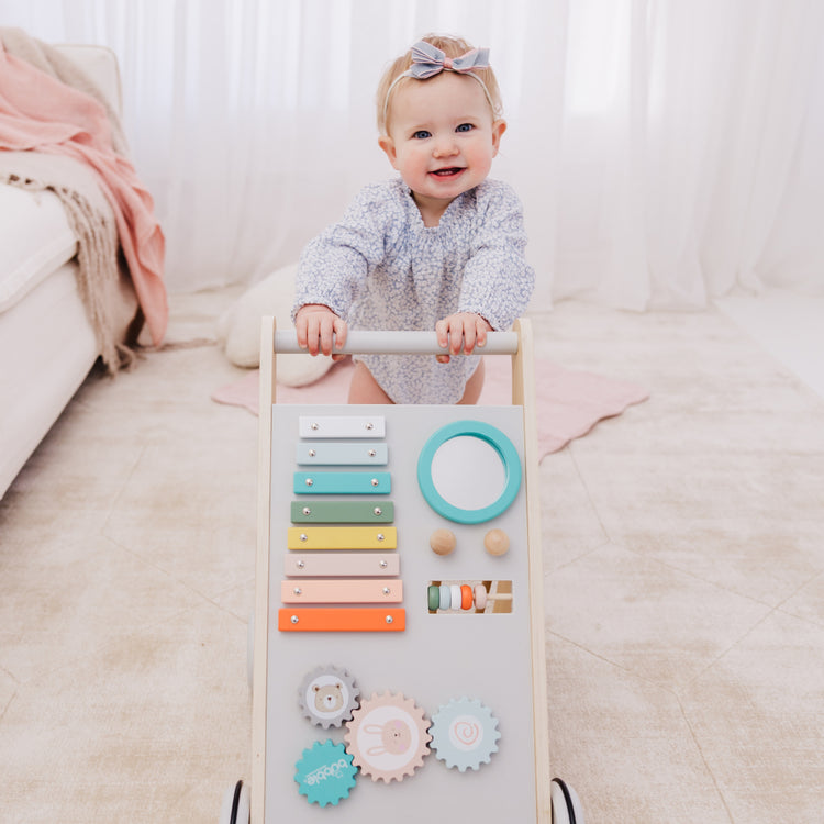 Baby playing with a colorful wooden activity board on a light-colored couch.