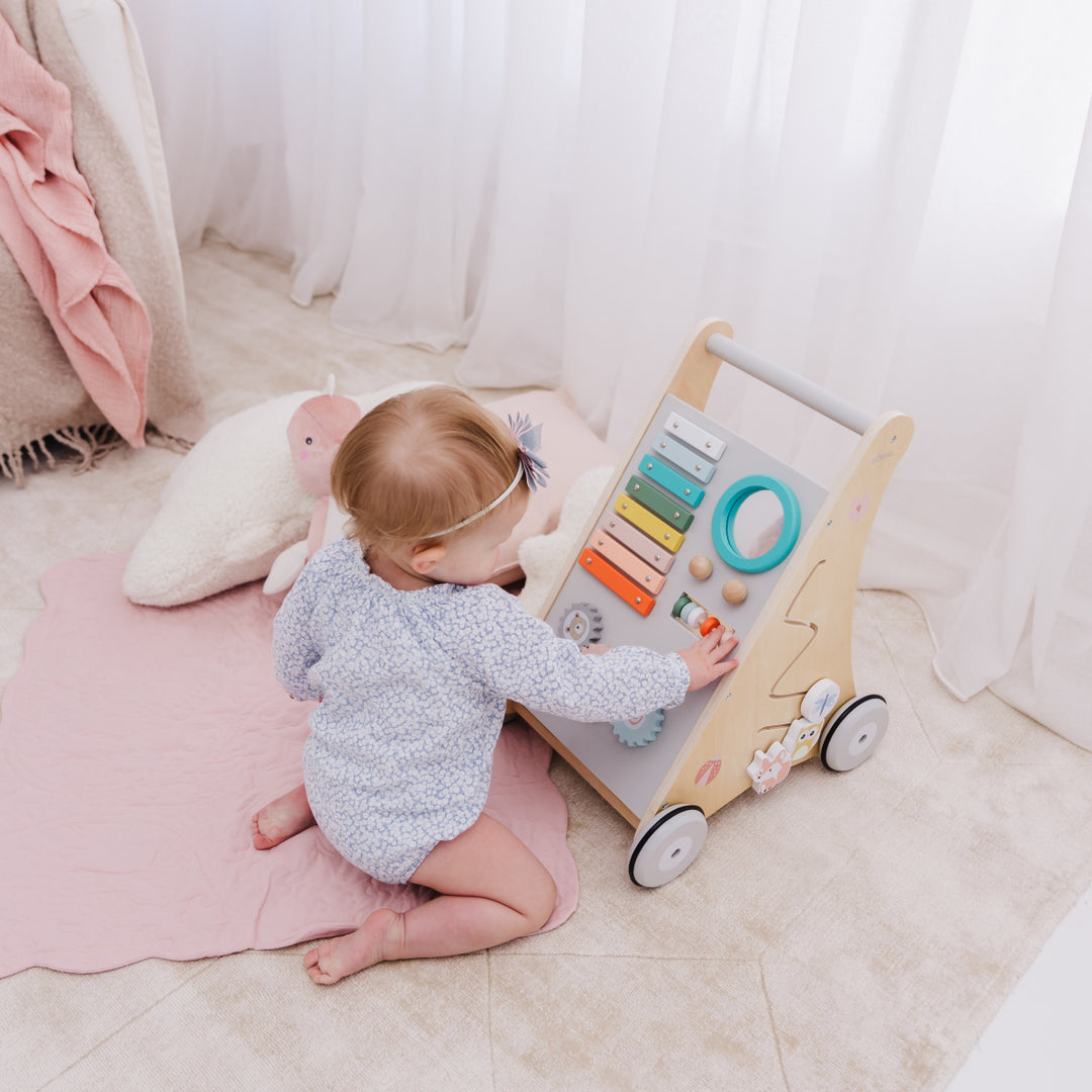 Baby playing with a wooden toy on a soft surface