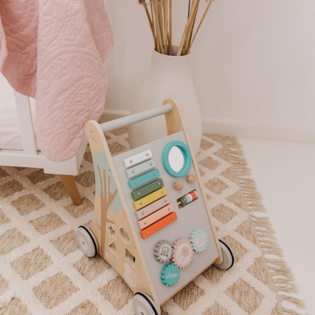 Children's wooden activity toy with colorful buttons on a patterned rug