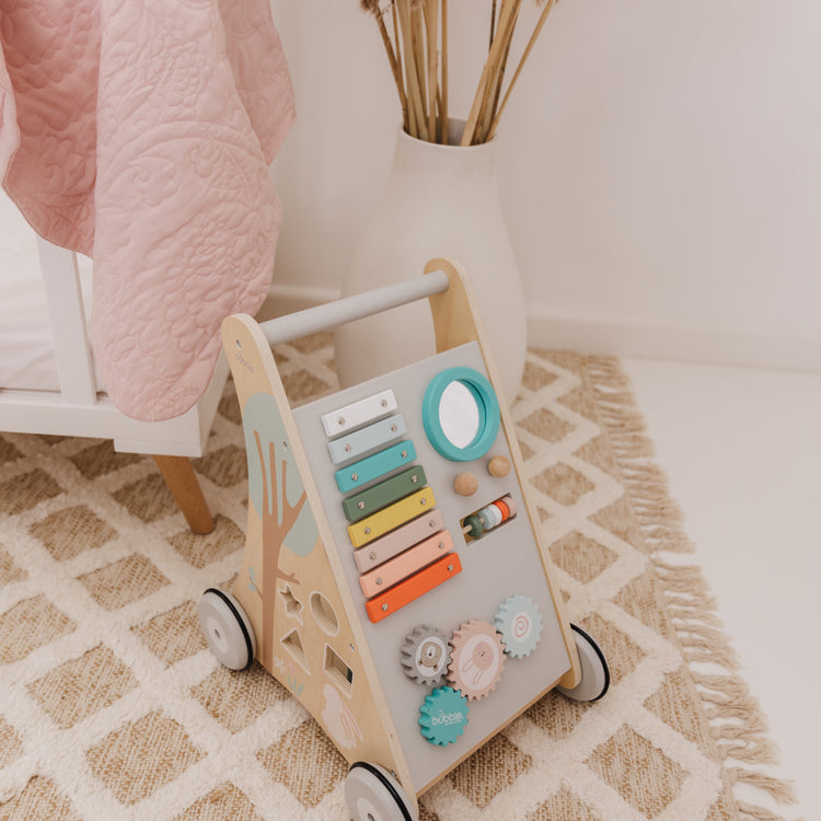 Children's wooden activity toy with colorful buttons on a patterned rug