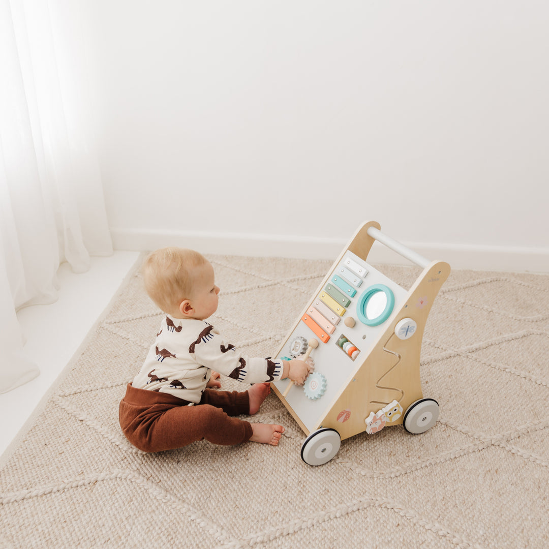Baby playing with a wooden toy on a carpeted floor