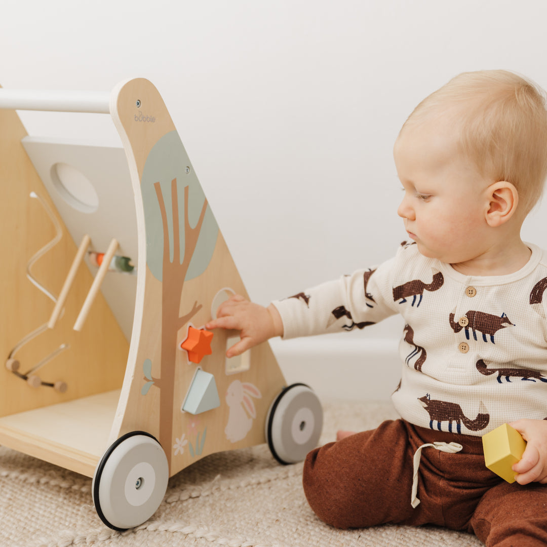 Child playing with a wooden toy and colorful blocks on a carpeted floor.