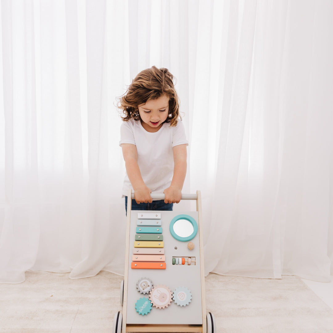 Child playing with a wooden toy ladder against a white curtain backdrop