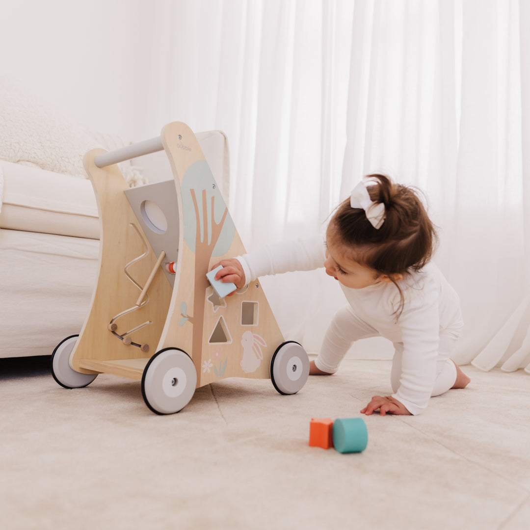 Child playing with a wooden toy on a light-colored floor.