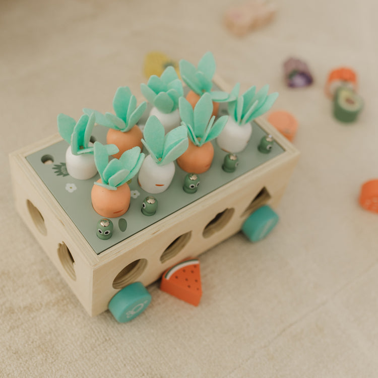 Toy bus with green plants and colorful wheels on a beige surface