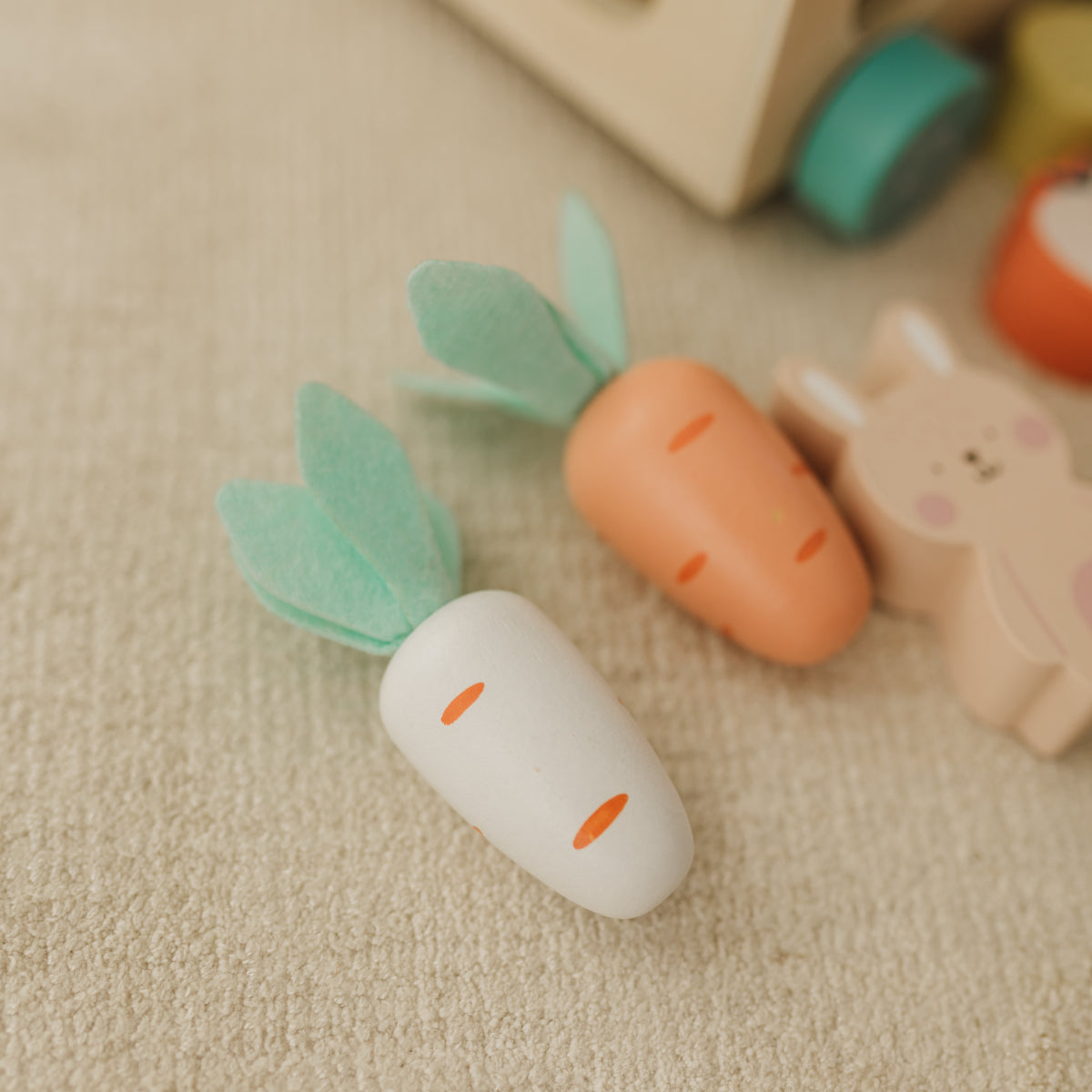Toy carrot and radish on a beige surface