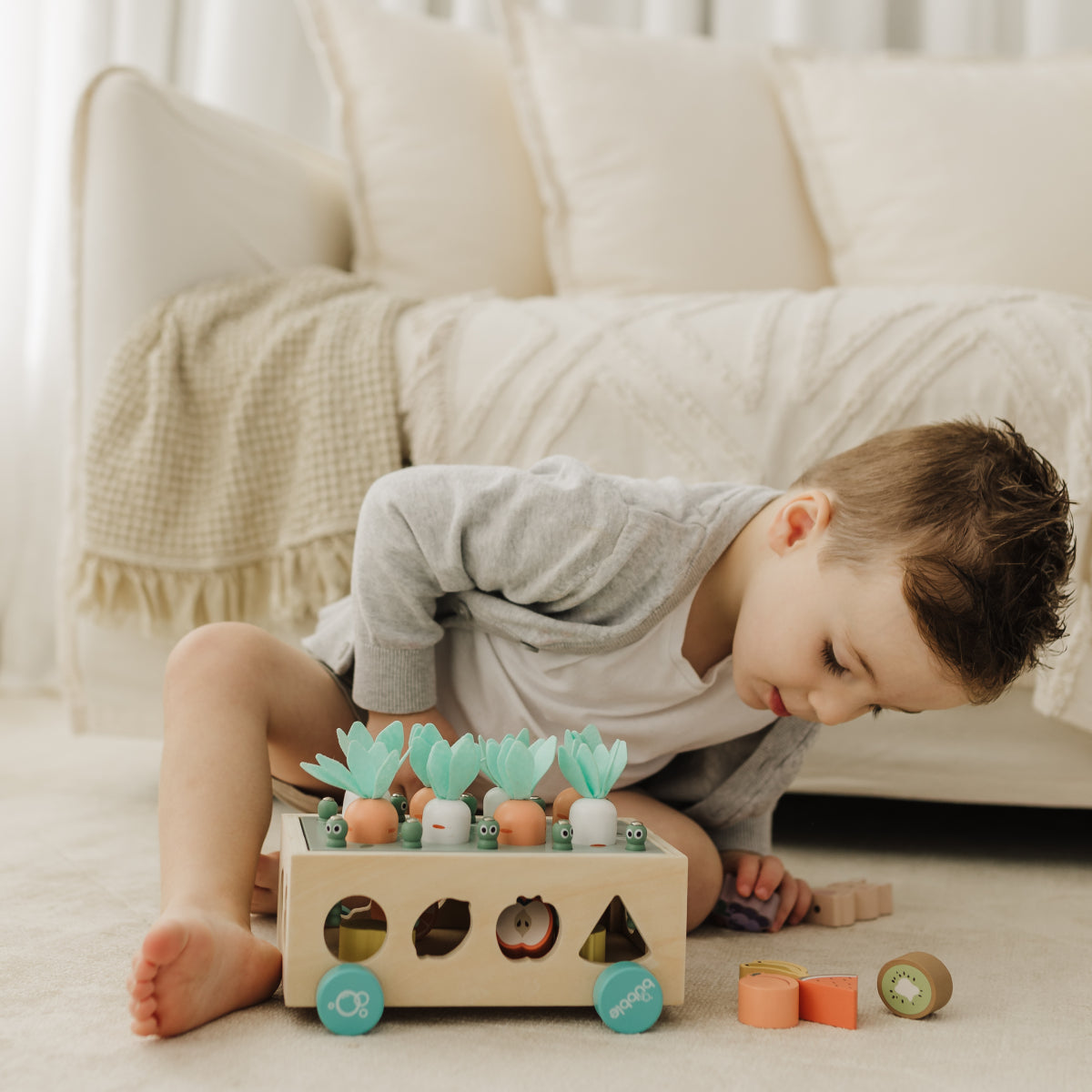 Child playing with a wooden toy on a light-colored floor.