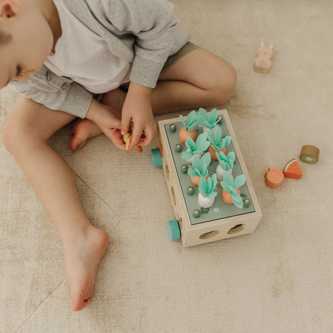 Child playing with a wooden toy on a beige carpet