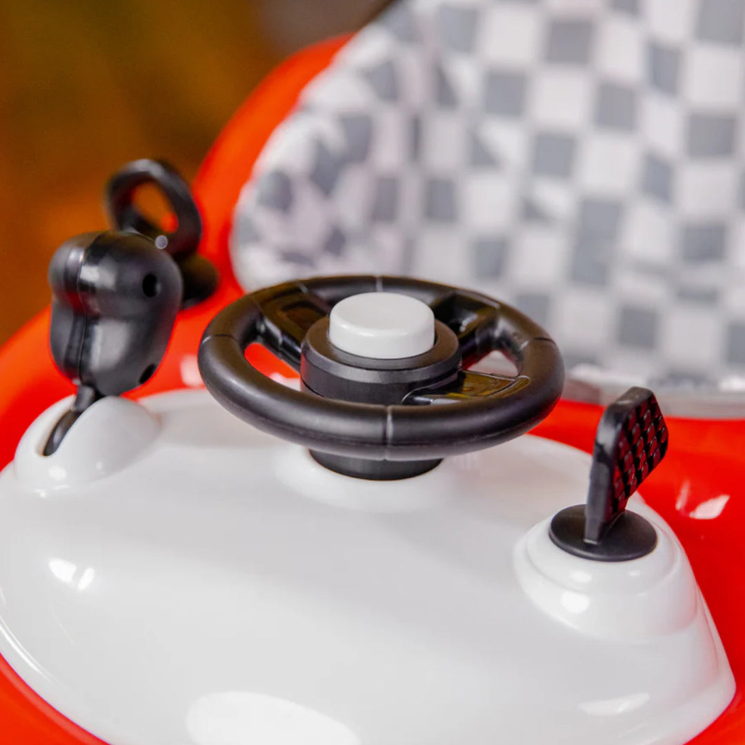 Close-up of a toy car with steering wheel and dashboard against a blurred checkered background