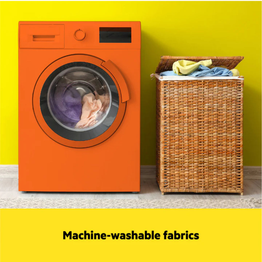 Orange washing machine with a wicker basket containing clothes against a yellow wall.