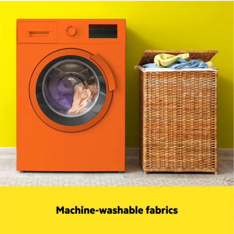 Orange washing machine with a wicker basket containing clothes against a yellow wall.
