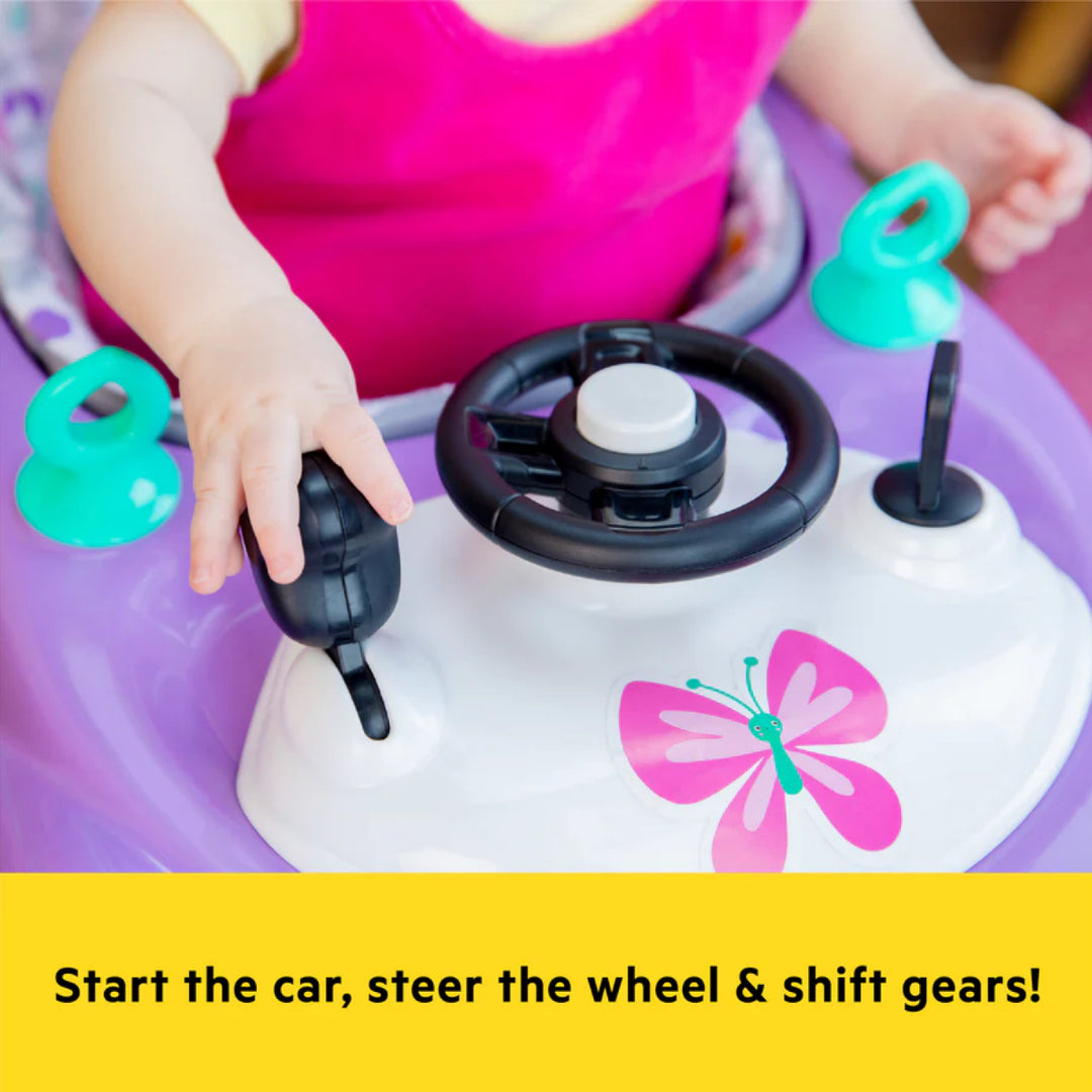Child playing with a toy car set on a purple surface, featuring a steering wheel and gear shift.