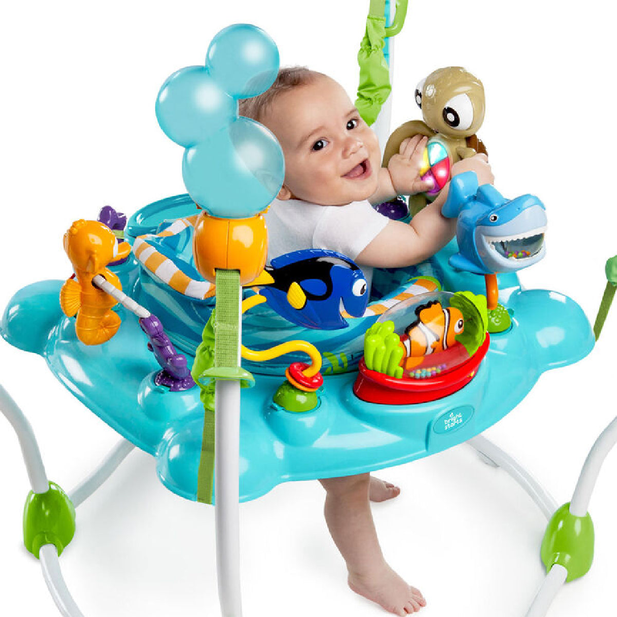 Baby playing in a colorful baby jumper with various toys on a white background