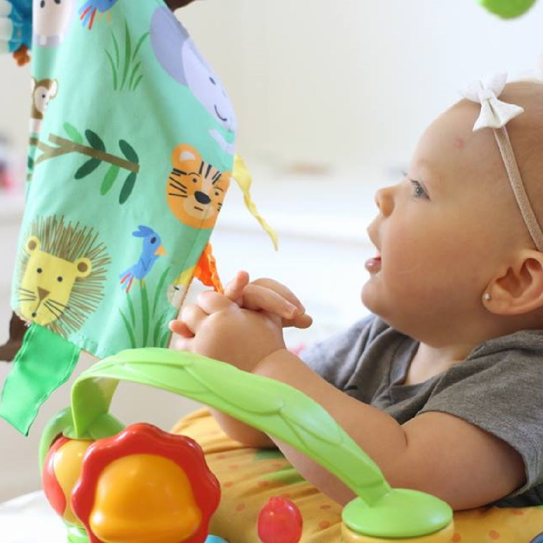 Baby playing with a colorful toy near a crib with animal patterns
