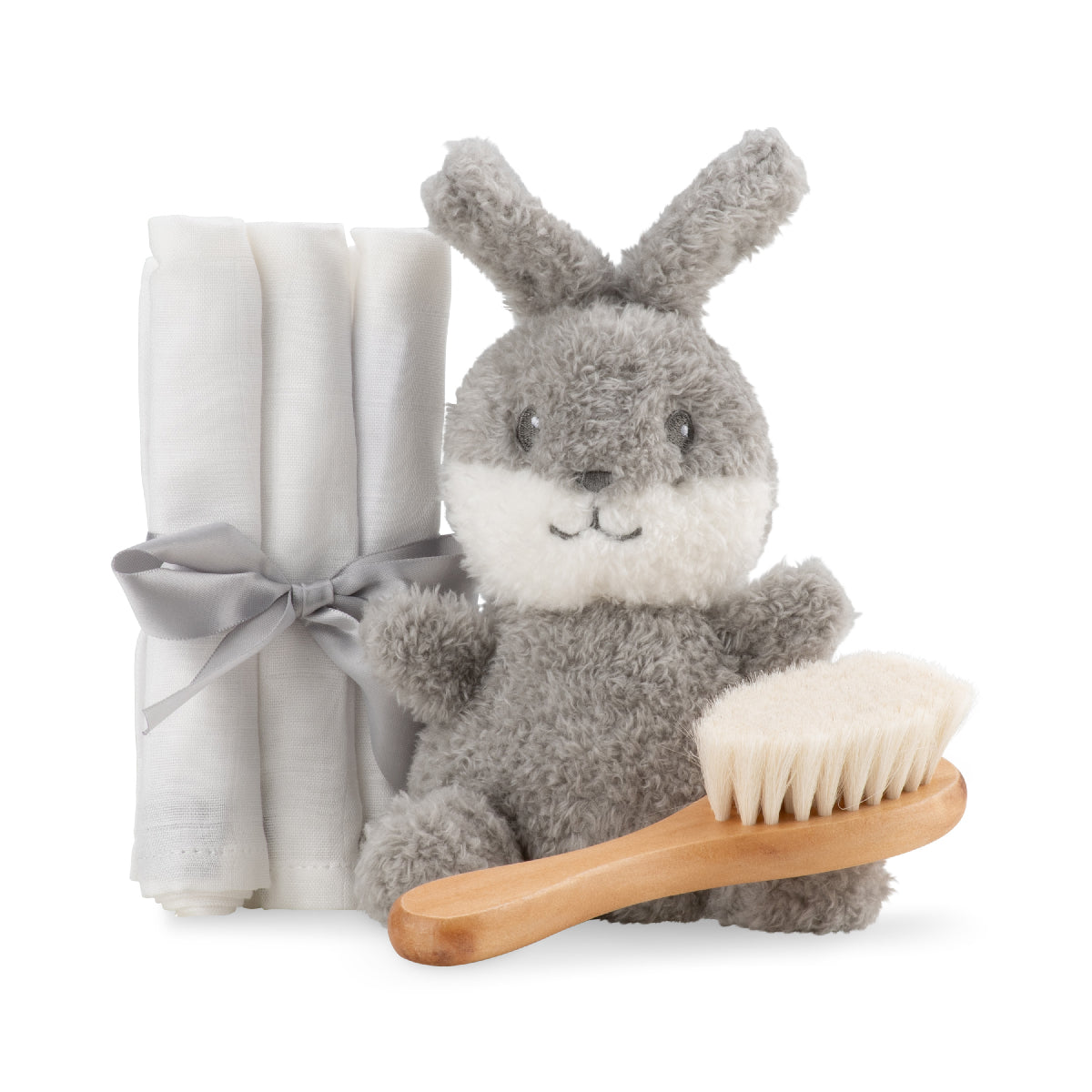 Gray plush bunny toy with a wooden brush and white blanket on a white background