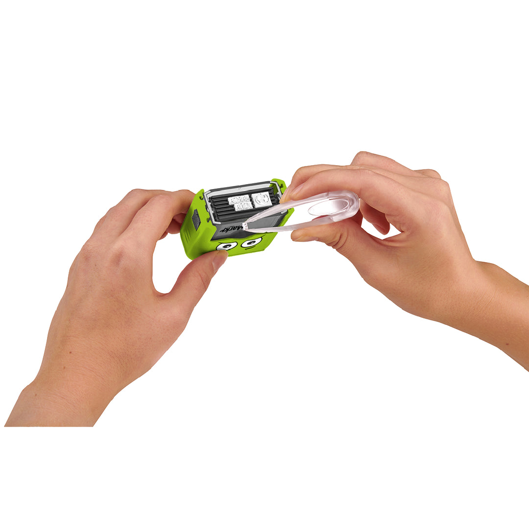 Green toy with a face being held by hands on a white background