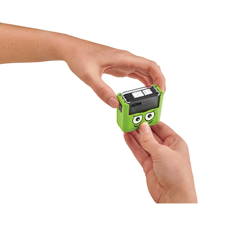 Small green device with cartoonish face held by a person's hand on a white background