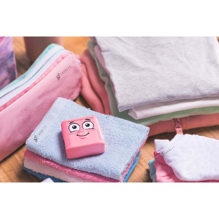 Pink cartoon character on a folded towel with folded clothes in the background
