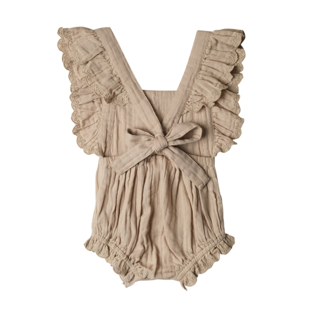 Beige romper with ruffled straps and a bow on a white background