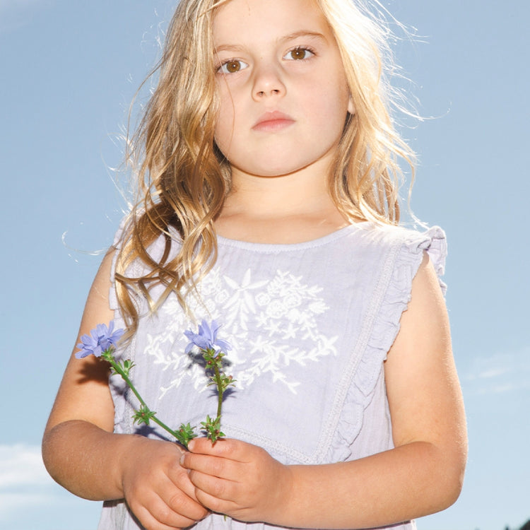 Young girl holding flowers against a clear blue sky