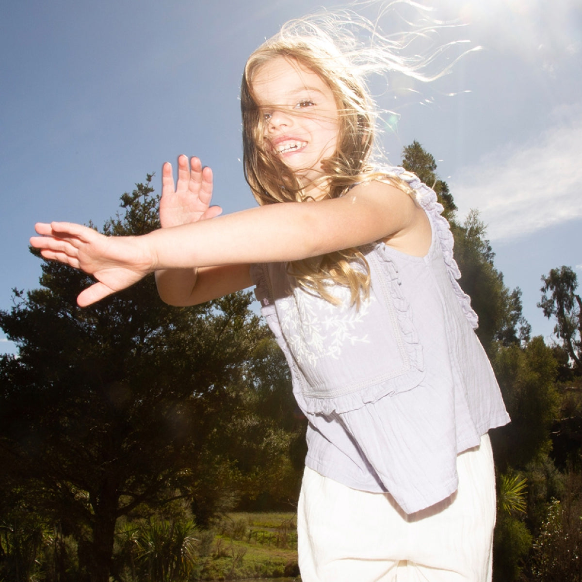 Young girl with arms outstretched in a natural setting
