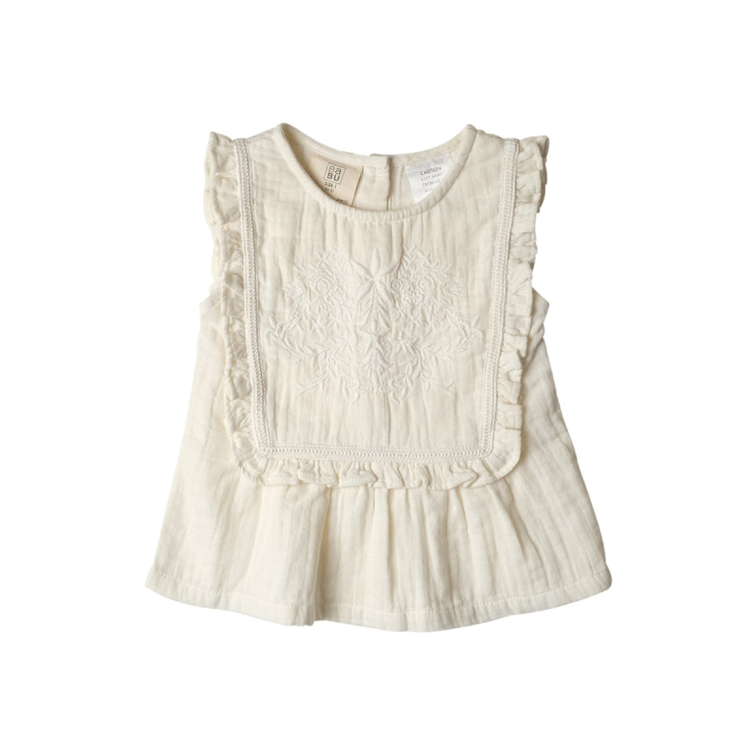 White sleeveless top with ruffled details on a white background
