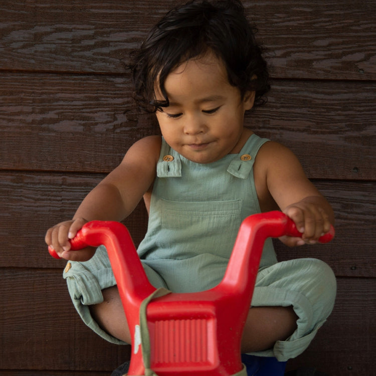Child playing with a red toy on a wooden floor