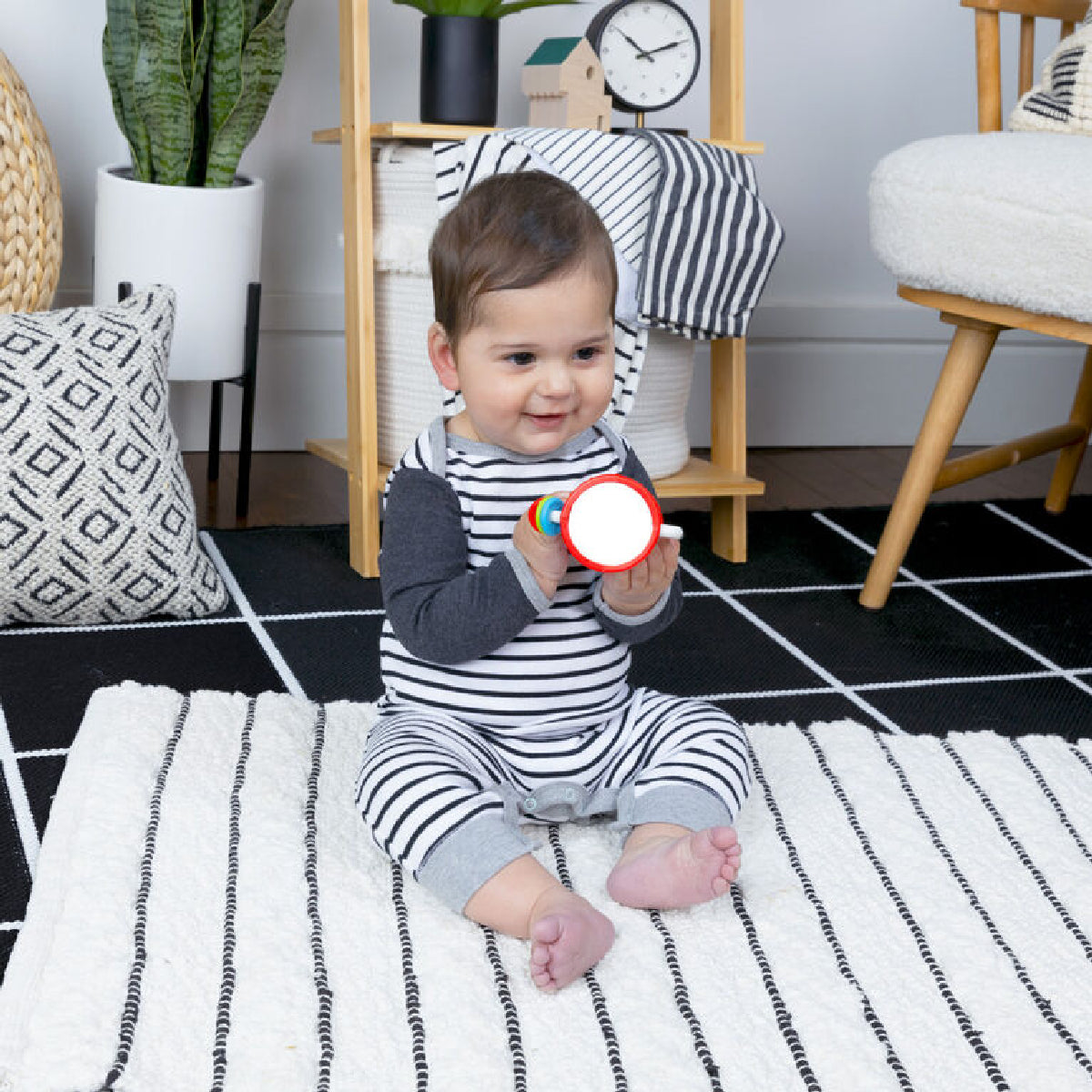 Baby sitting on a rug in a room with toys and furniture