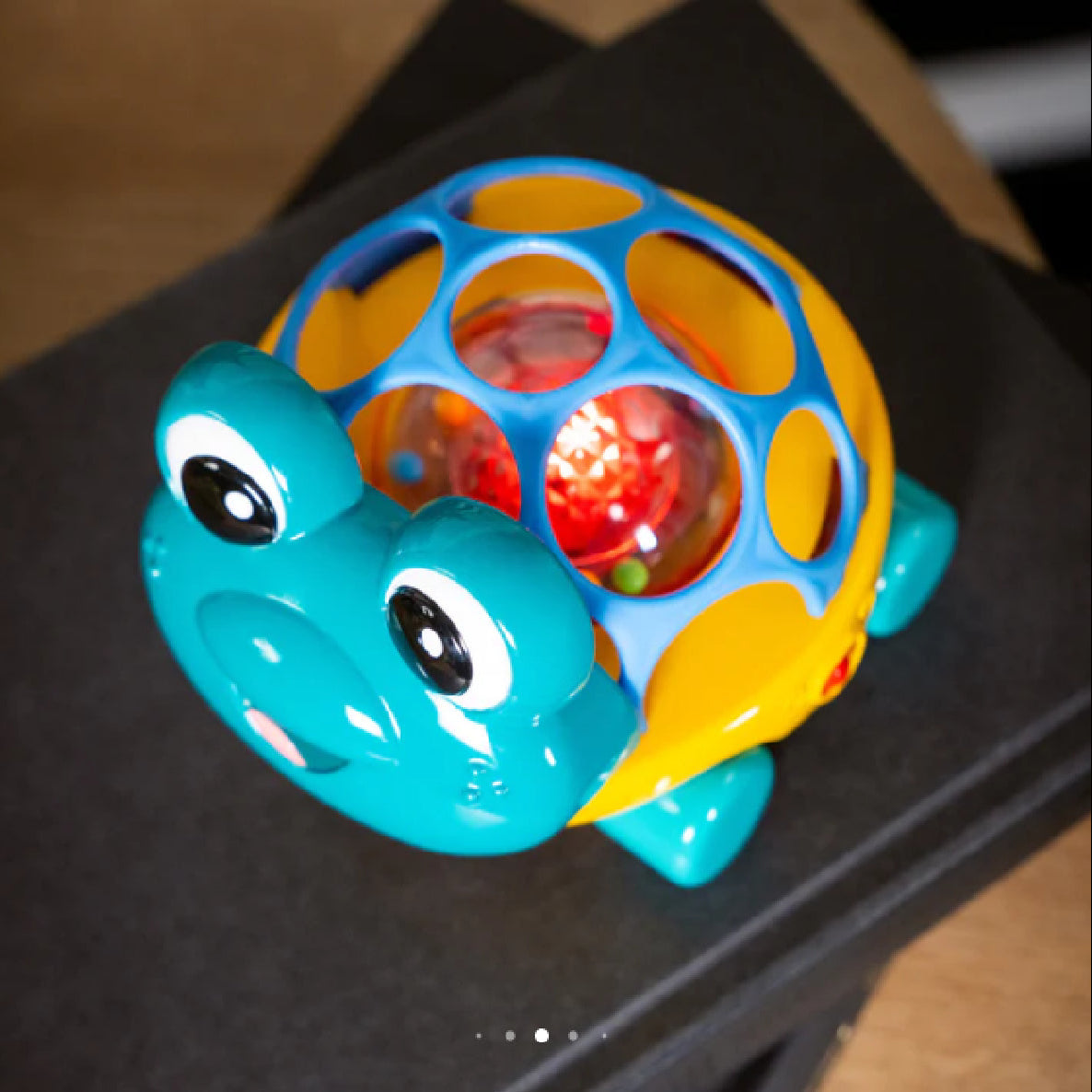 Colorful turtle-shaped toy with a transparent ball on a dark surface