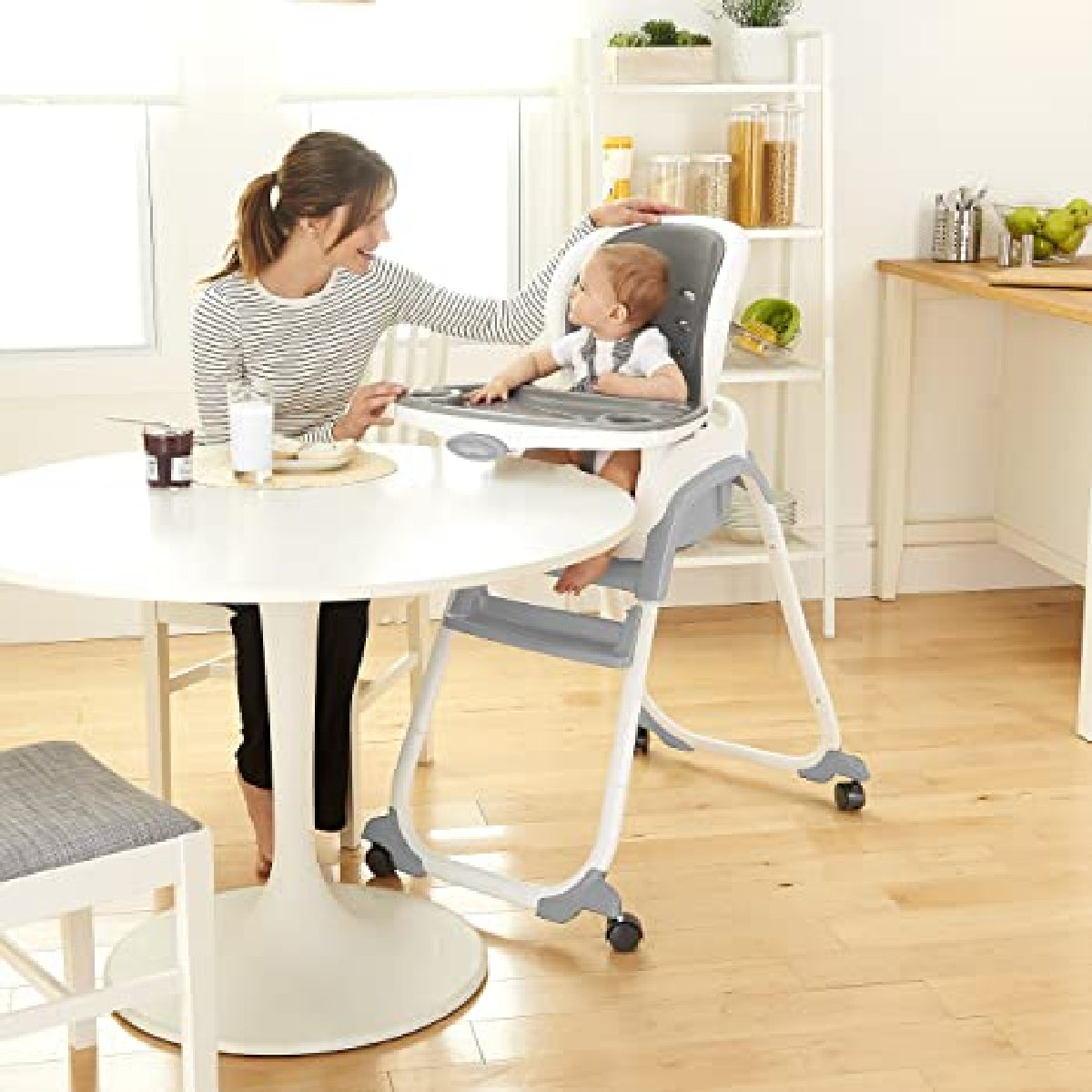 Woman with a child in a high chair at a dining table in a home setting