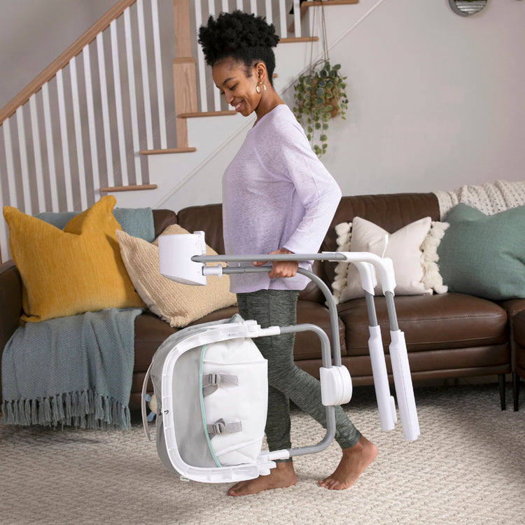 Woman carrying a white mobility scooter in a living room.