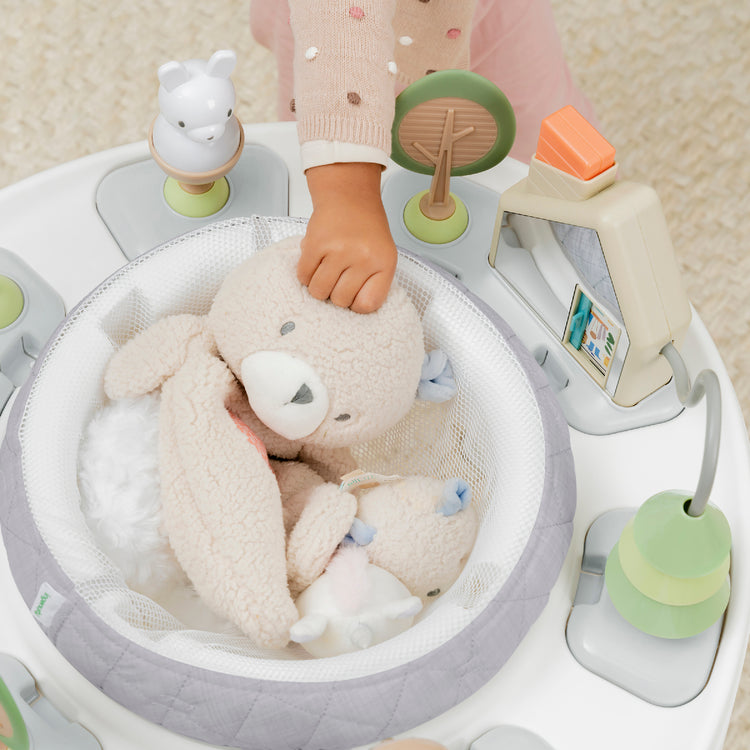 Baby play gym with toys and a plush teddy bear, featuring a child's hand reaching in.
