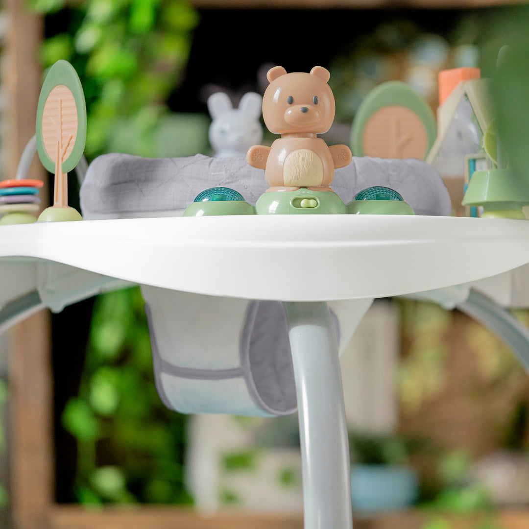 Toy bear on a white surface with blurred greenery in the background