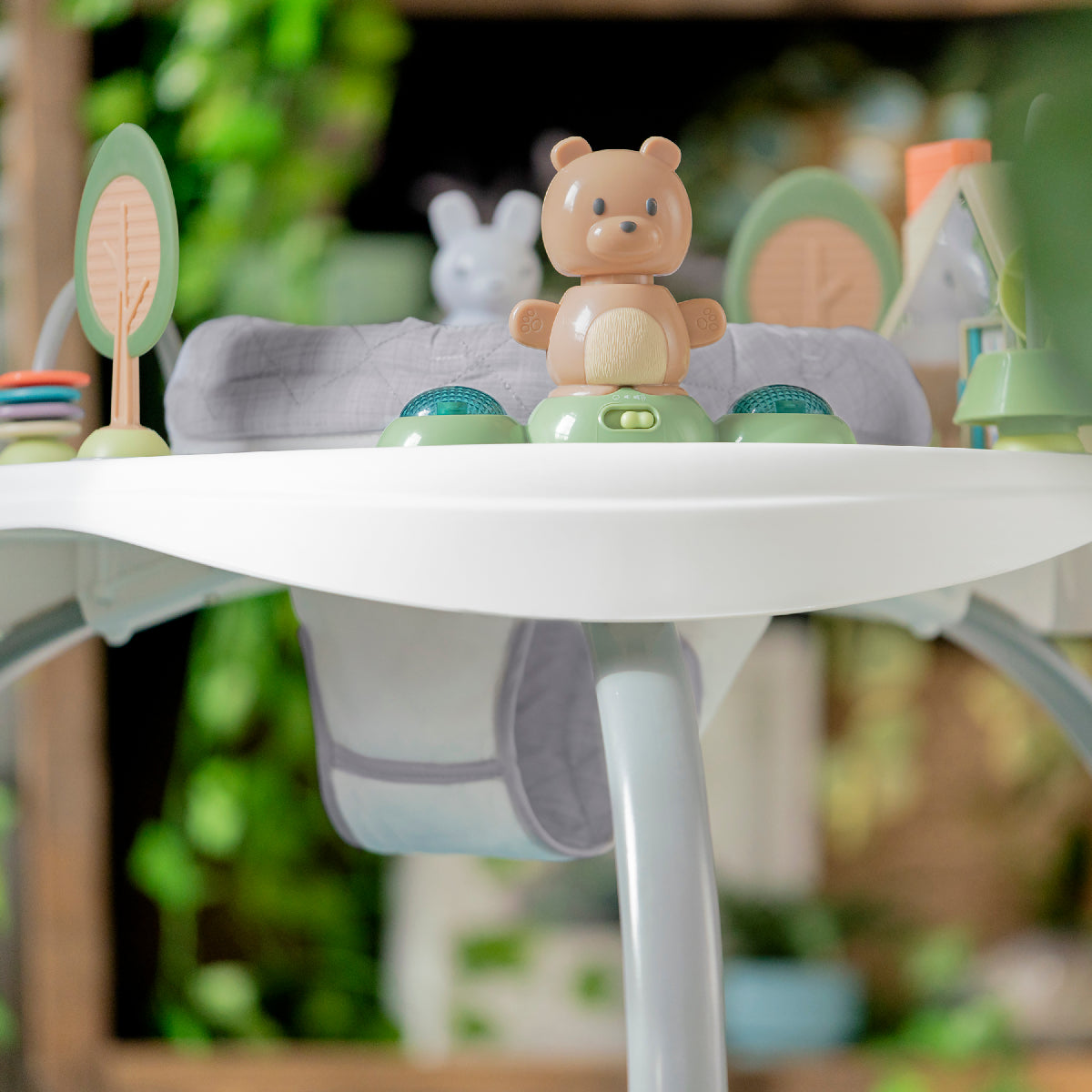 Toy bear on a white surface with blurred greenery in the background
