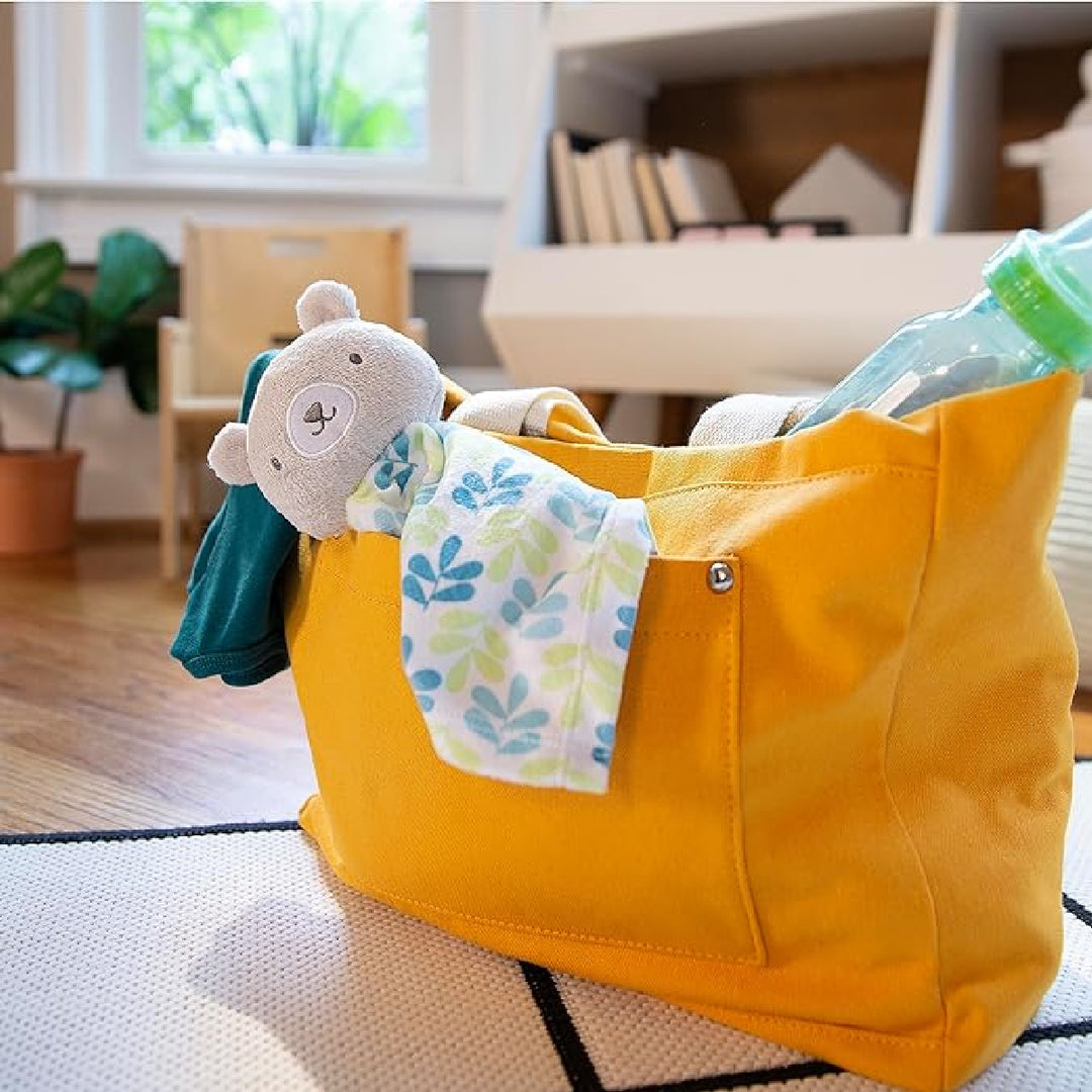 Yellow bag with a teddy bear toy and bottle on a checkered floor
