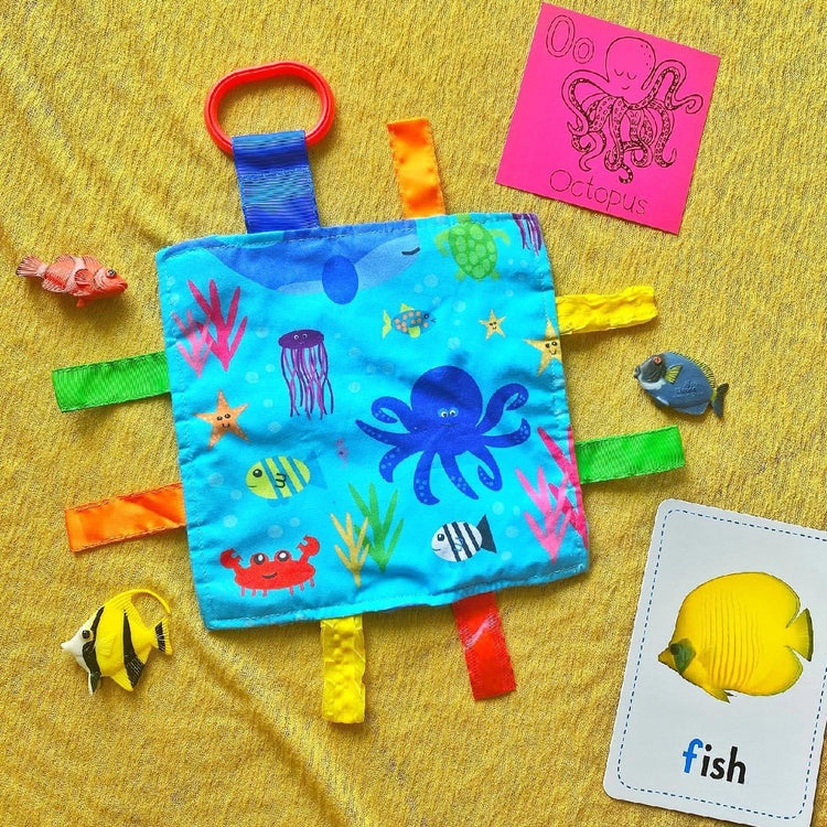 Colorful fabric toy with ocean-themed tags and cards on a yellow background