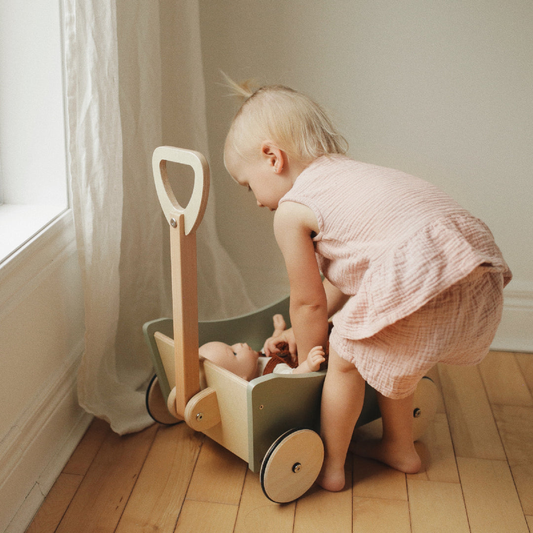 Child playing with a toy wheelbarrow indoors