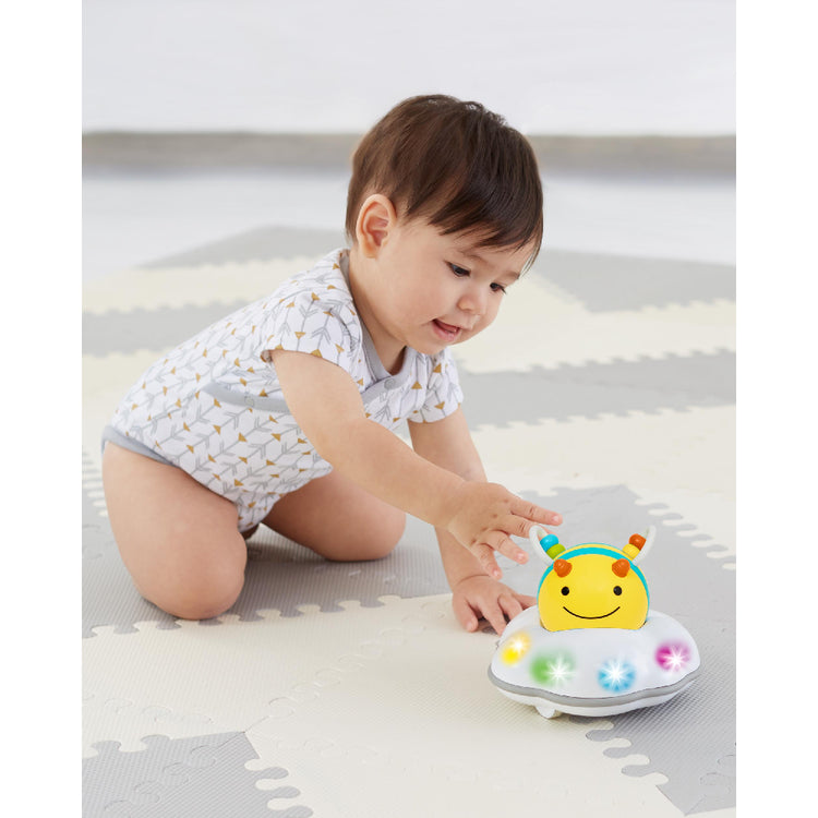Baby playing with a colorful toy on a light-colored floor.