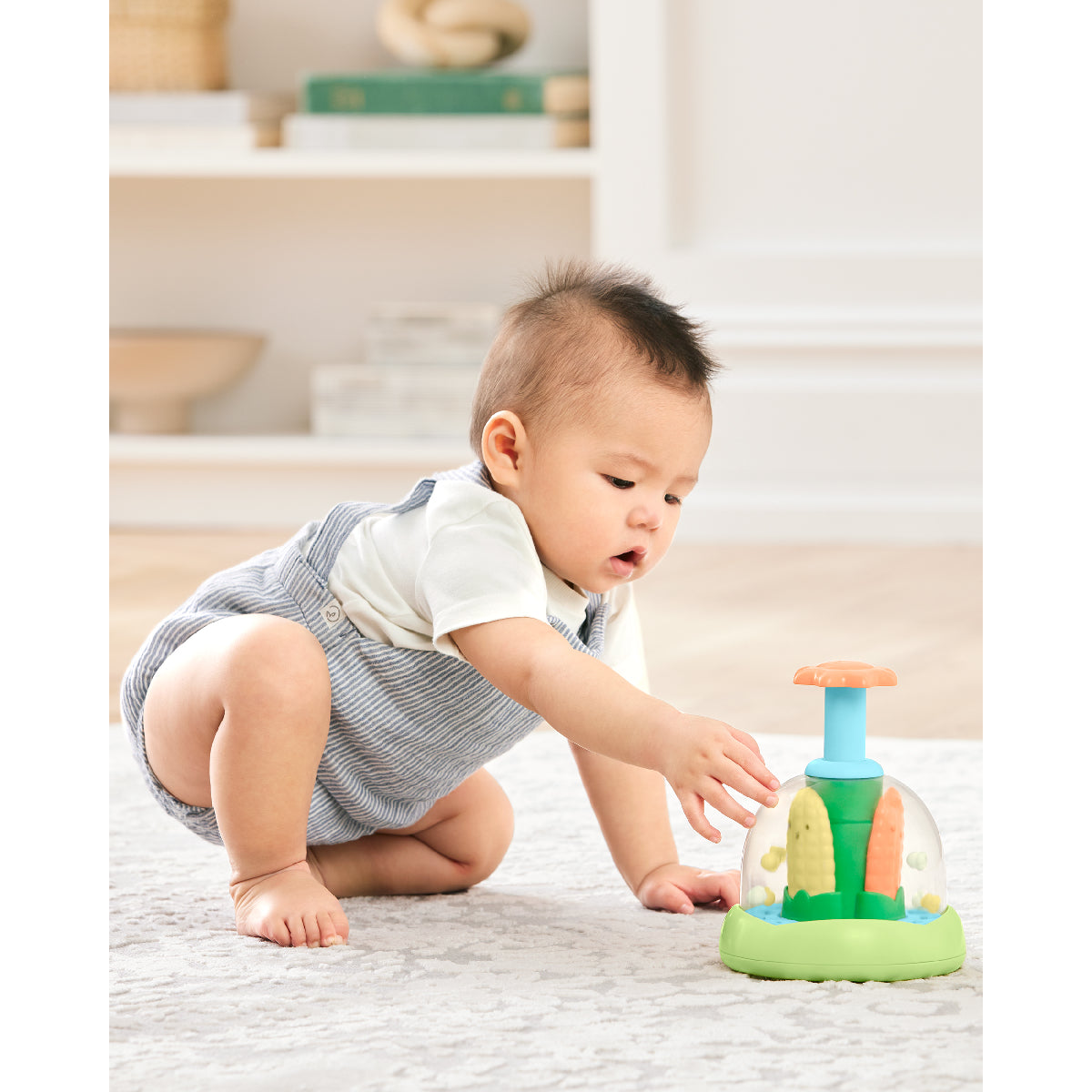 Baby playing with a colorful toy on a light-colored floor.