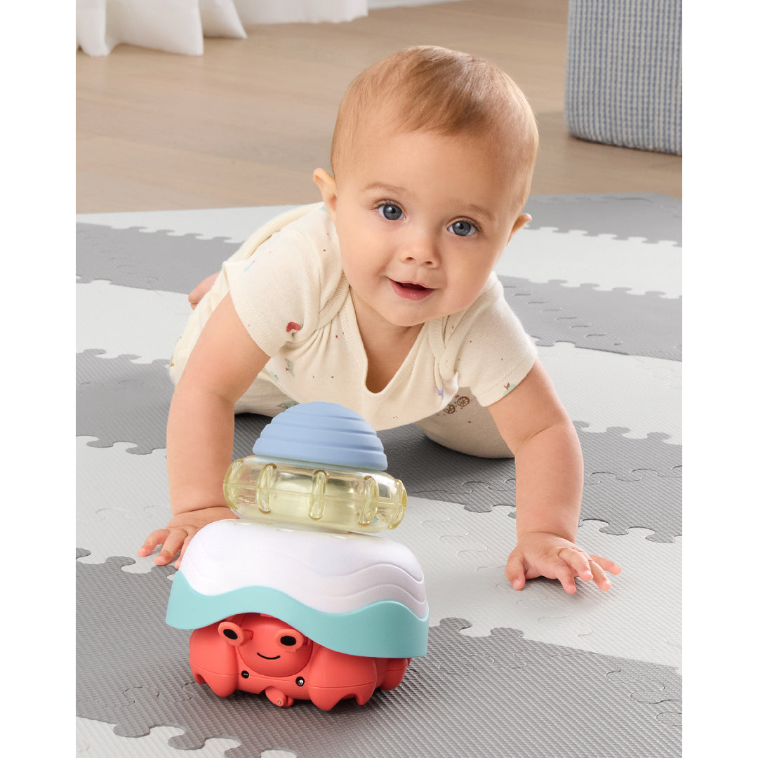 Baby playing with a colorful toy on a soft play mat