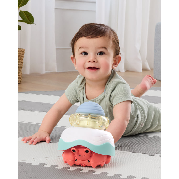 Baby playing with a colorful toy on a mat indoors