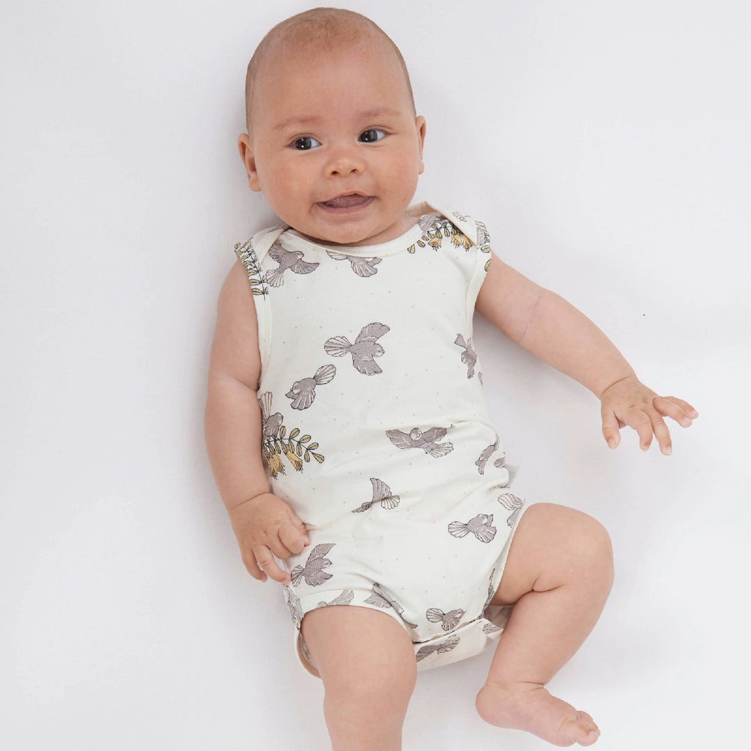 Baby wearing a white romper with gray floral patterns on a white background