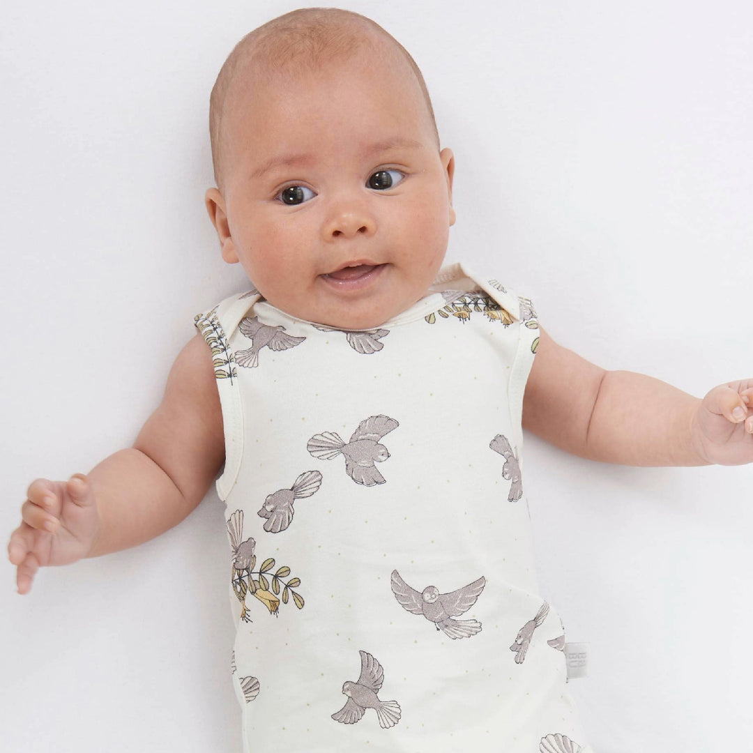 Baby wearing a sleeveless outfit with bird pattern on a white background