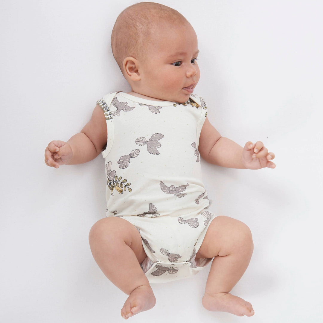 Baby wearing a white sleeveless romper with gray floral patterns on a light gray background