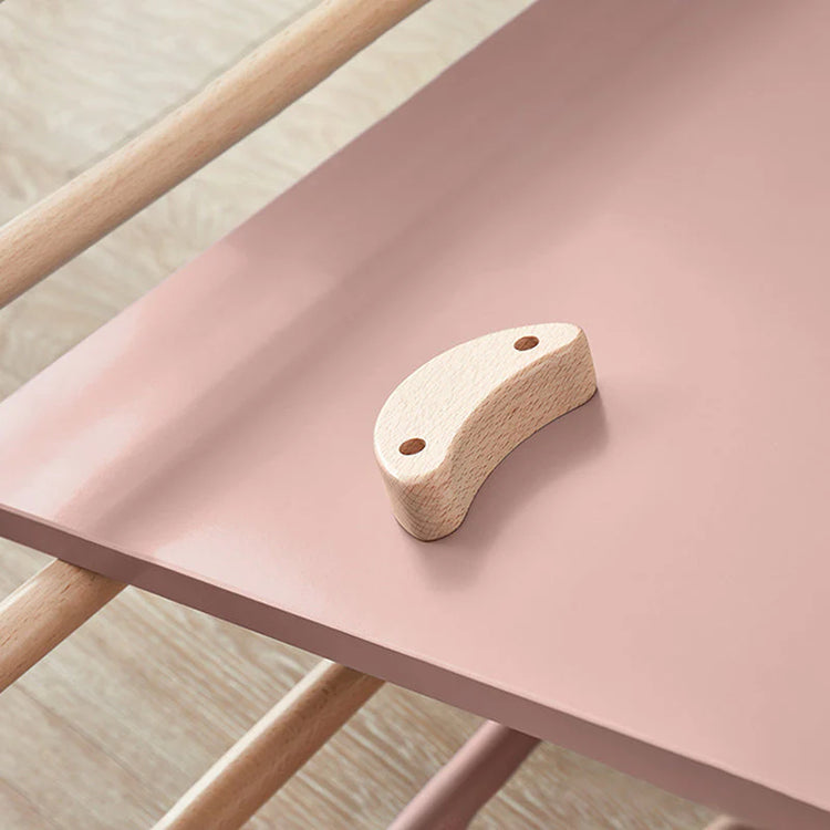 Wooden chair with a pink seat and wooden backrest on a light wooden floor.