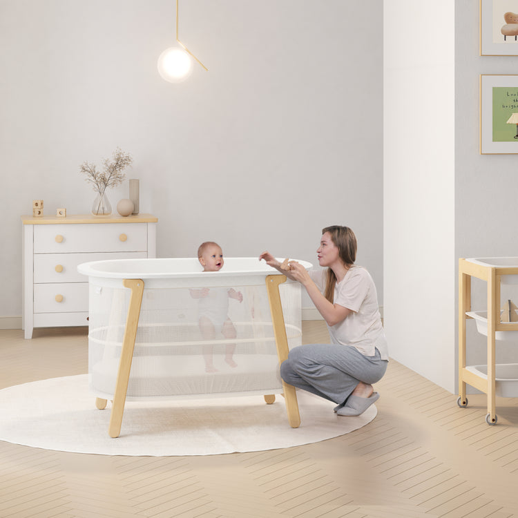 Woman and baby in a modern nursery with a white crib.